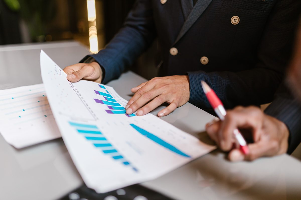 Nærbillede af personer, der gennemgår finansielle grafer og nøgletal under et driftsmøde.